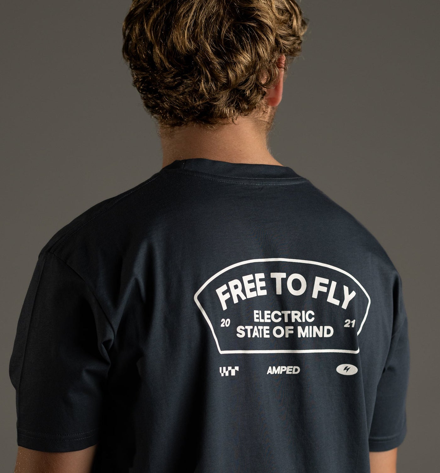 Person wearing a black t-shirt with text on the back against a gray background