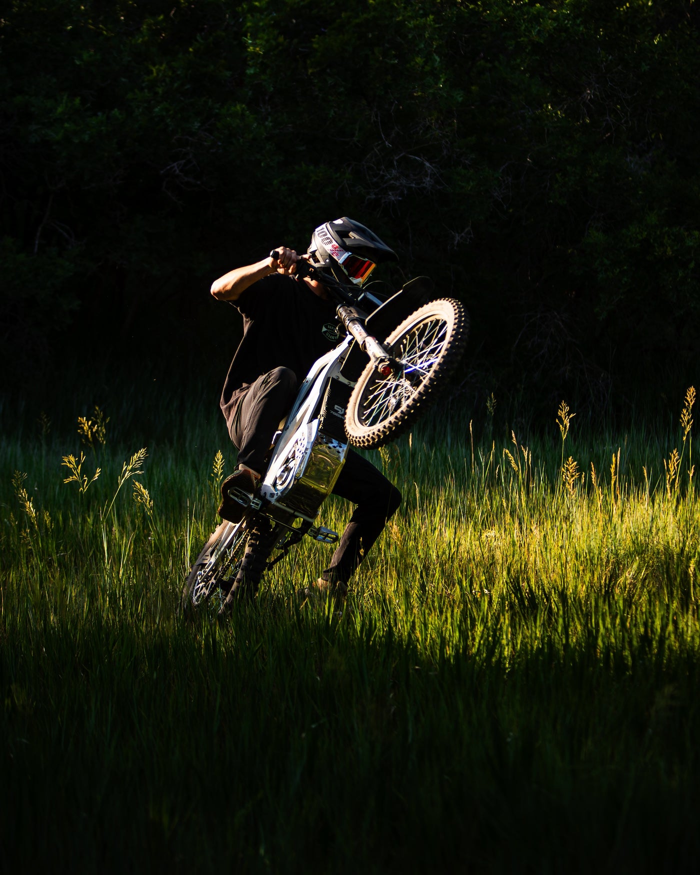 Person riding a dirt bike in a grassy field with a dark background
