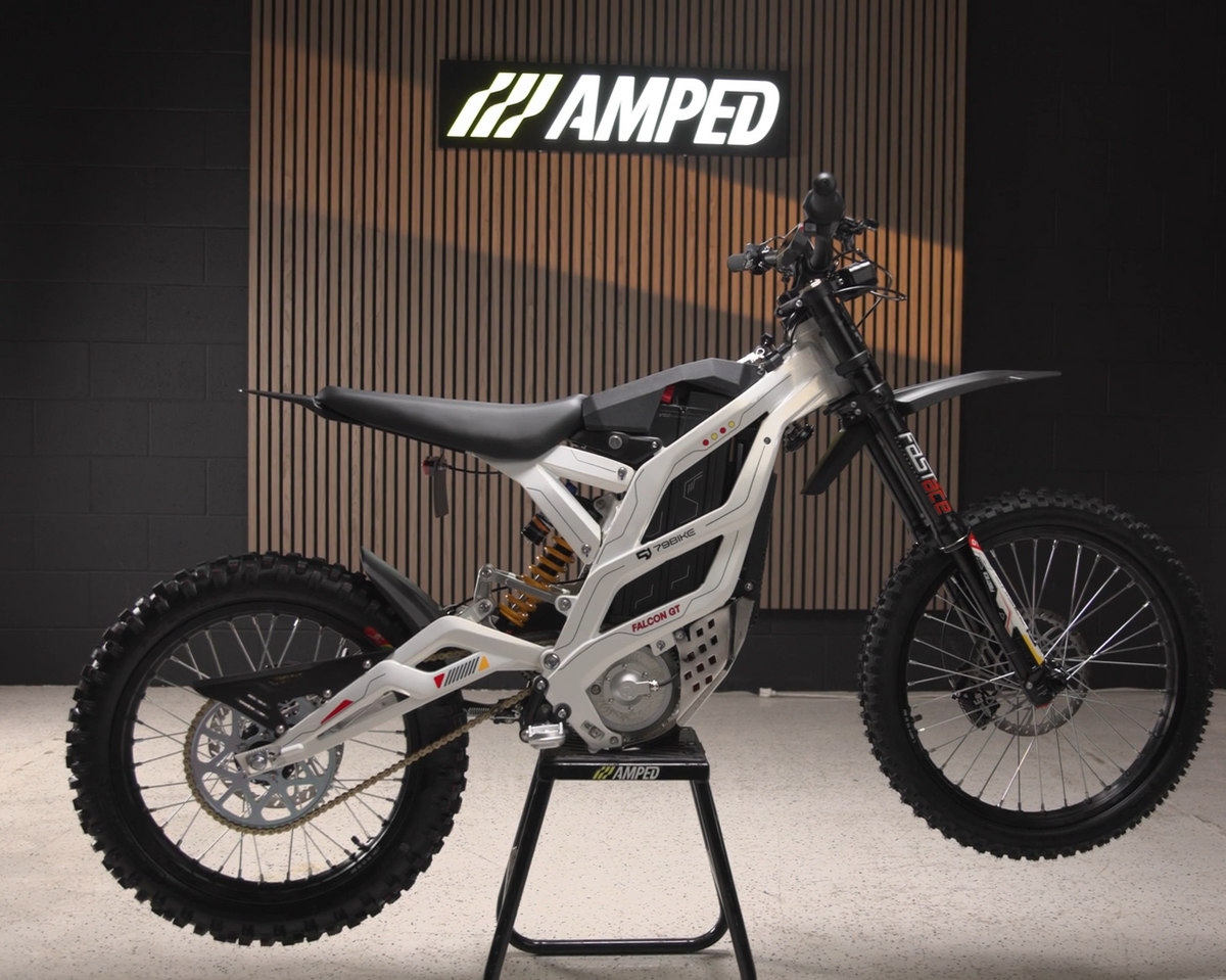 White electric bike on a stand with Amped logo in the background