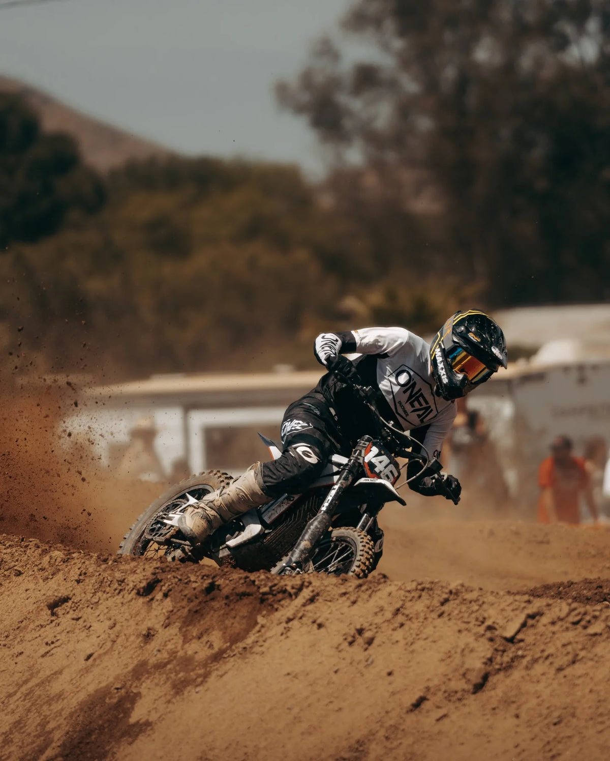 Arctic Leopard rider railing a berm, dirt flying, at the track