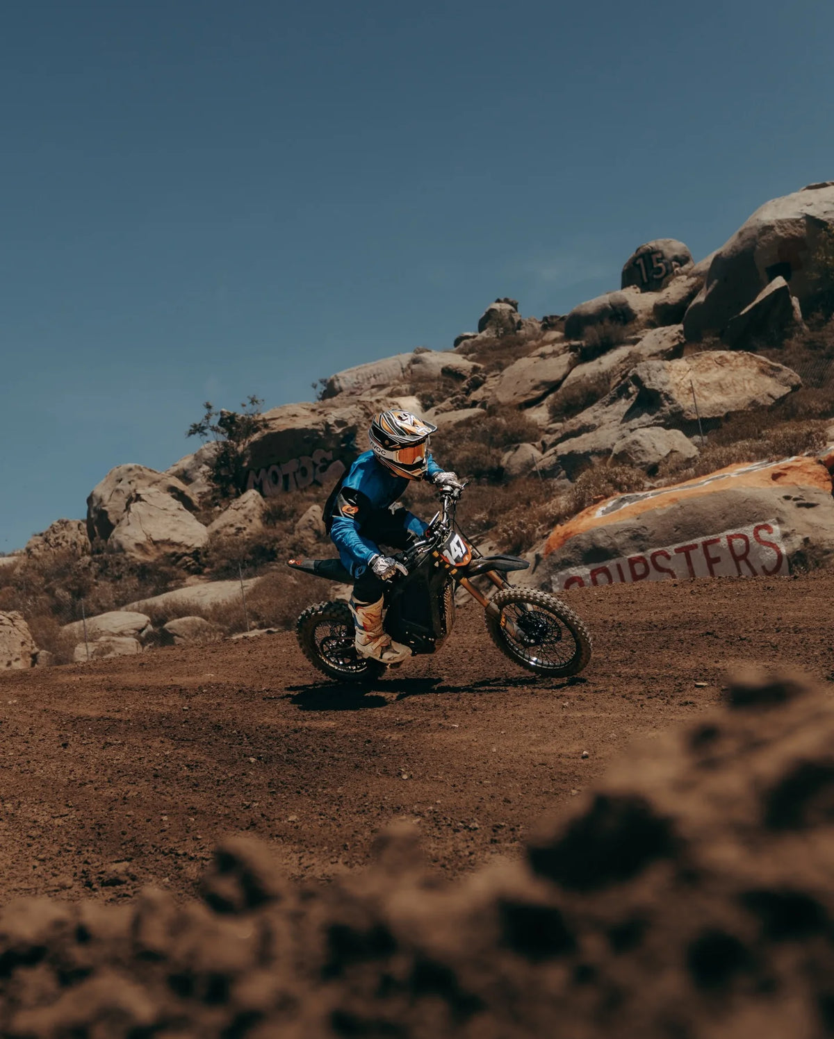 Arctic Leopard rider climbing a rocky dirt section at the track